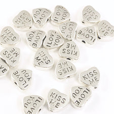 silver jewerly beads that are heart shaped and have I love you kiss me engraved on them
