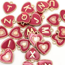 pink heart shaped jewelry charms with letters on them
