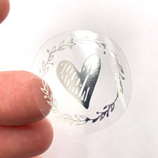Silver and clear sticker that has a heart and leaves on it