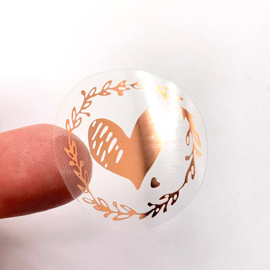 Rose gold and clear sticker that has a heart and leaves on it