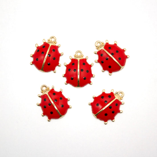 Five red and gold jewelry charms that look like ladybugs