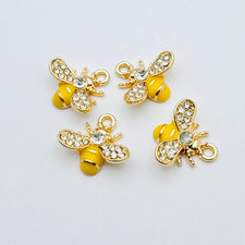 Four bee shaped jewerly charms that are yellow, gold and have glass rhinestones