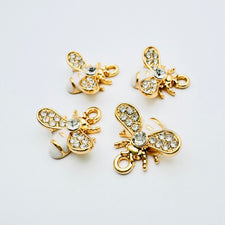 bee shaped jewerly charms that are white, gold and have glass rhinestones