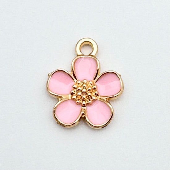 pink and gold jewelry charm in the shape of a five petal flower