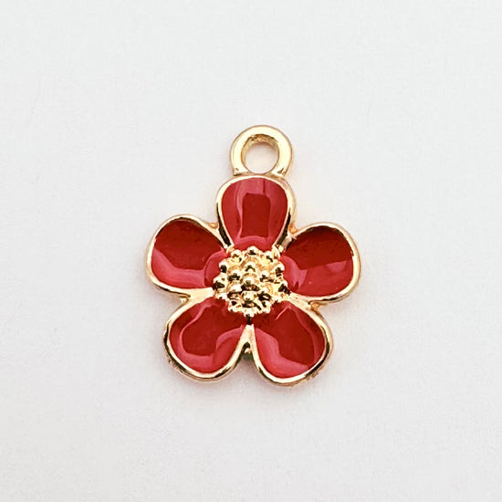 Red and gold jewelry charm in the shape of a five petal flower