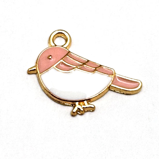 pink white and gold jewelry charm in the shape of a bird