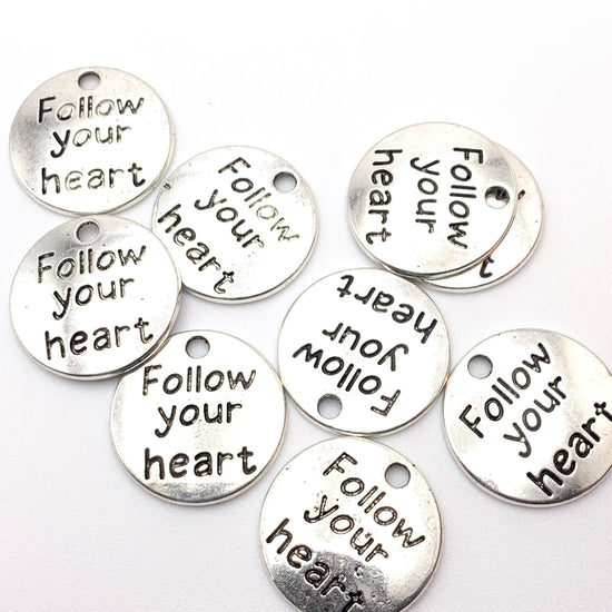 round silver jewerly charms with the words follow your heart