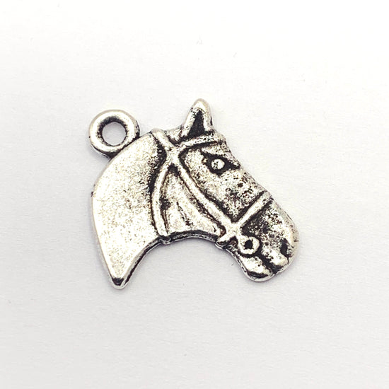 silver color jewelry charm in the shape of a horse head