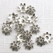 pile of flower shaped silver beads caps