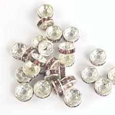 25 jewelry beads that are shiny silver with purple rhinestones 