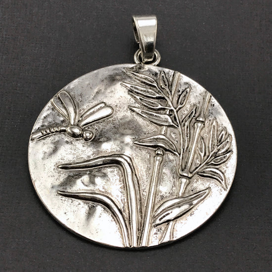large silver jewerly pendant with dragonfy and reeds on it