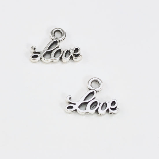 2 tiny jewelry charms that say the word love