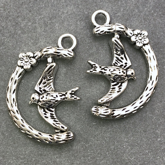 spinning jewelry charms of a bird on a branch