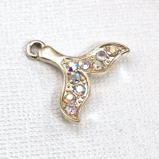 gold jewelry charm shaped like a whale tail with rhinestones