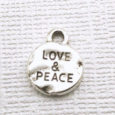 round silver jewelry charm with love and peace engraved in it