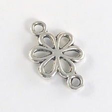 close up of a silver colour jewelry charm shaped like a daisy