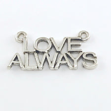 close up of a silver jewelry pendant that says love always