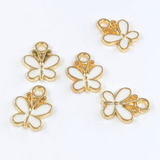 white and gold jewelry charms shaped like butterflies