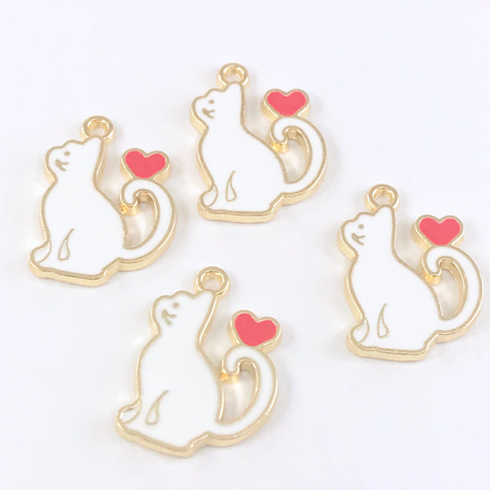 4 white and gold jewelry charms that are shaped like cats