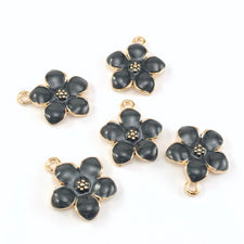 5 jewelry charms that look like black and gold flowers