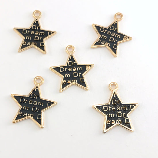 black and gold star shaped jewelry charms with the word dream on them