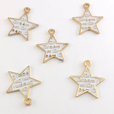 white and gold star shaped jewelry charms with the word dream on them
