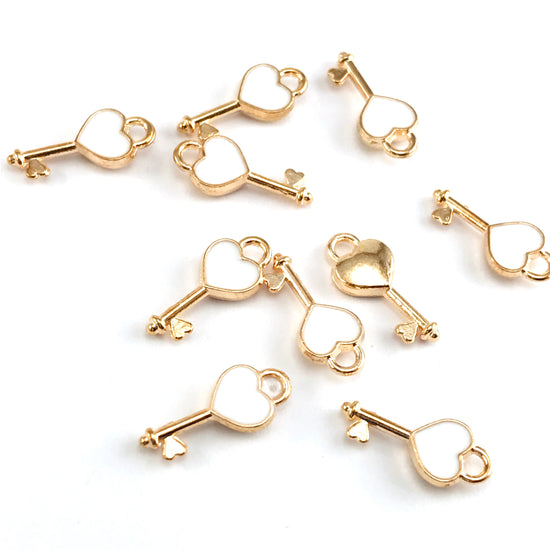 10 key shaped jewerly charms that are gold and white in colour