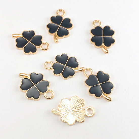 black and gold jewelry charms that look like four leaf clovers