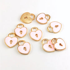 10 pink and gold jewelry charms that are shpaed like hearts and have a key hole design in the middle