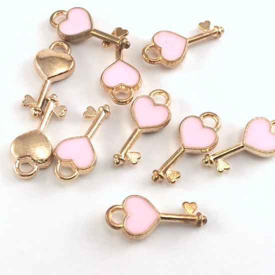 pink and gold jewelry charms shaped like keys