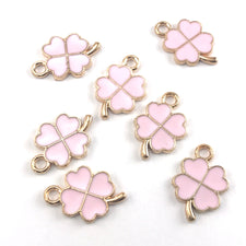 pink and gold colour jewelry charms that look like founr leaf clovers