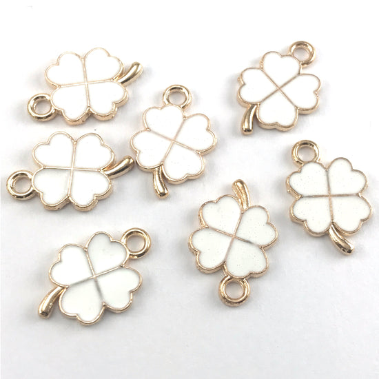 four leaf clover shaped jewerly charms that are white and gold