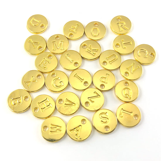 gold colour round charms with letters stamped on them