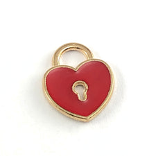 red and gold jewerly charm that is heart shaped with a keyhole