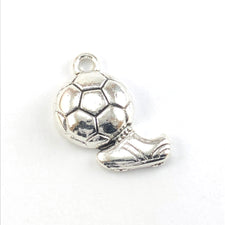 silver jewerly charm that looks like a ball with a shoe kicking it