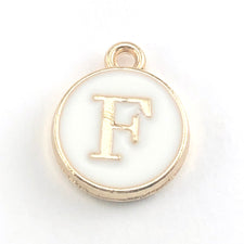 round white and gold jewerly charm with the letter F on it