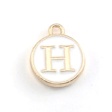 round white and gold jewerly charm with the letter H on it