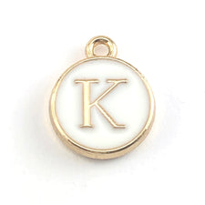 round white and gold jewerly charm that has the letter K on it