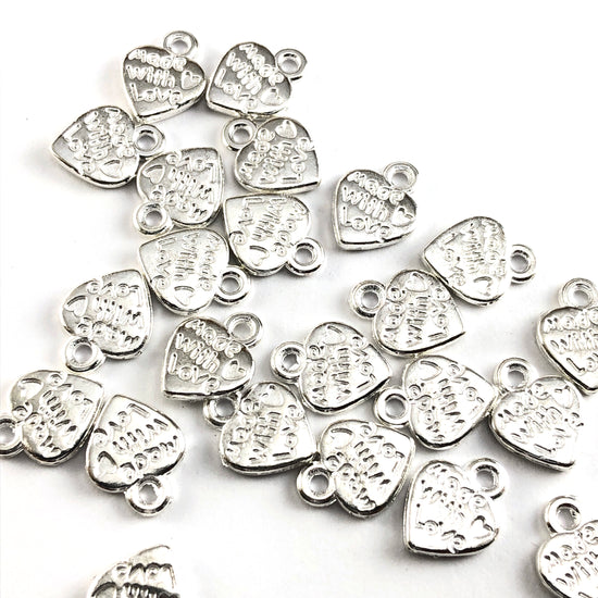 silver heart shaped jewelry charms with the words made with love on them