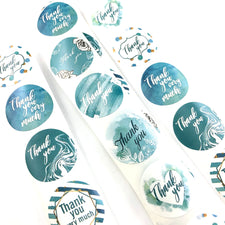turquoise and white round paper stickers that say thank you 