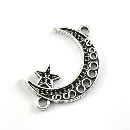 silver colour jewelry charm shaped like a moon with a star attached