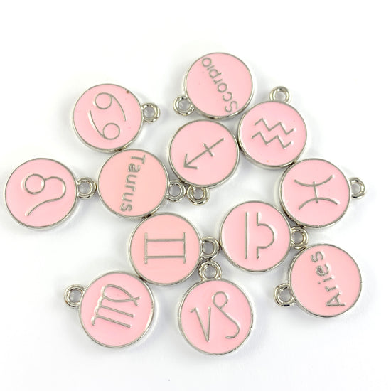 twelve pink and silver round jewerly charms with zodiac symbols on them