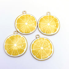 Four yellow and gold jewerly charms that look like lemon slices