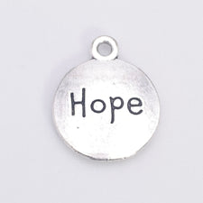 round silver jewerly charm with the word hope on it