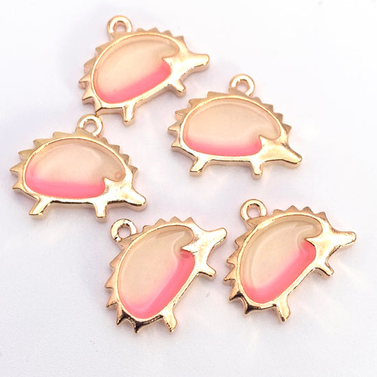 pink hello and gold jewelry charms that are shaped like hedgehogs