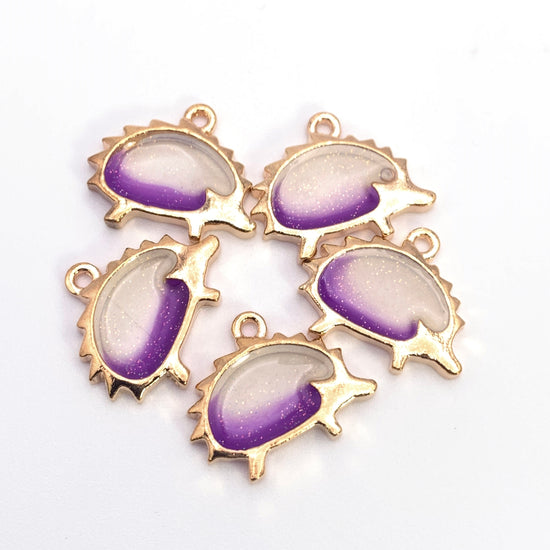 purple yellow and gold jewelry charms that are shaped like hedgehogs