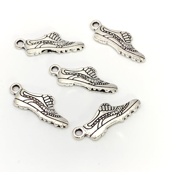 silver colour jewerly charms in the shape of running shoes