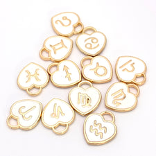 heart shaped white and gold jewerly charms with zodiac signs on them